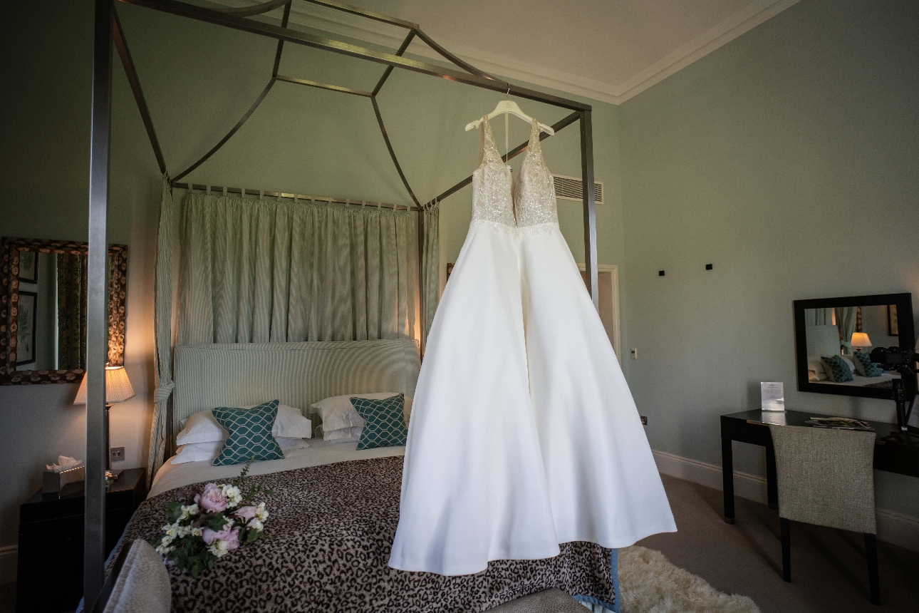 wedding dress hanging on a bed